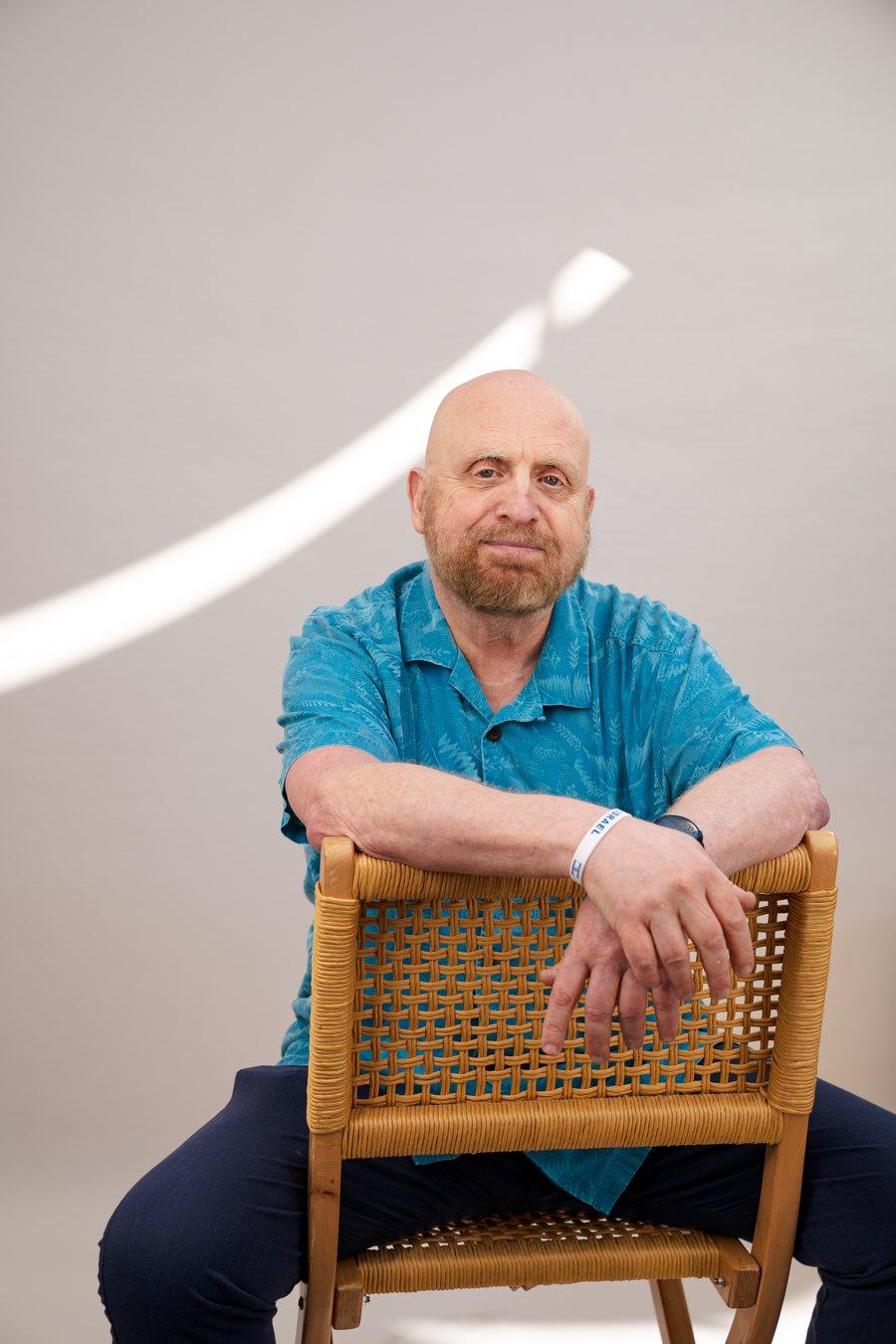 Roger Grossman, LMFT, seated and leaning on the back of a woven chair